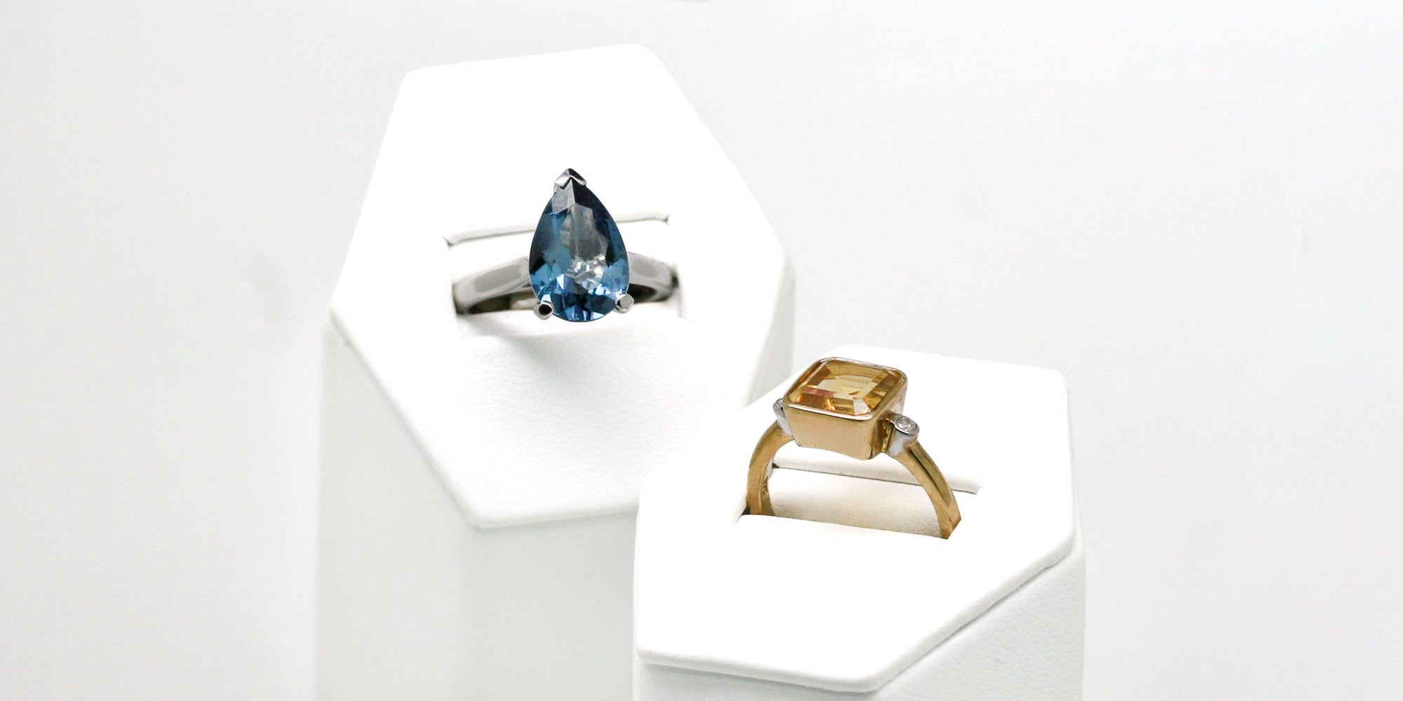 
                A topaz ring and a citrine ring in stands
              